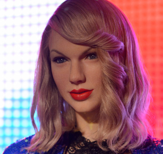 Taylor Swift- The medium blond flaxen color is drab and the bang curl is a bad rertro idea